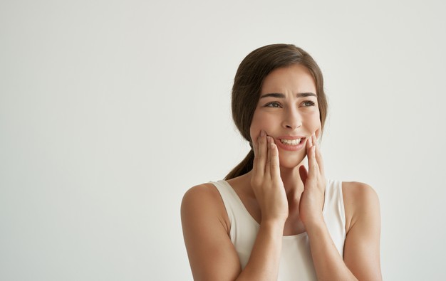 A lady experiencing jaw pain, also known as Temporomandibular Joint disorder. In this article we share all about jaw pain and how to manage the pain.
