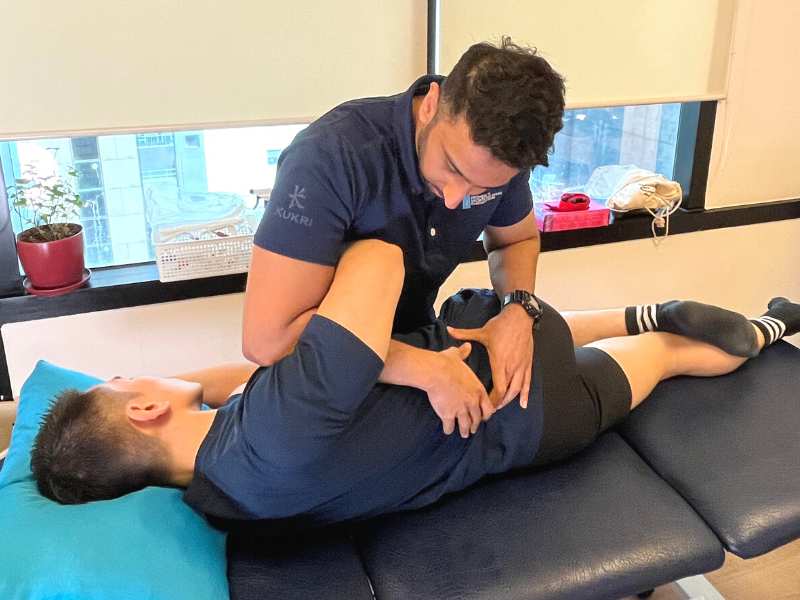 Gurjiven Singh, a physiotherapist at Prohealth Sports And Spinal Physiotherapy Centres Hong Kong, performing a lower back assessment on a client